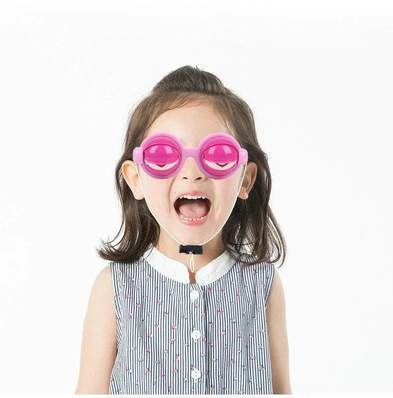 Child wearing pink eye-shaped funny glasses prank toy on white background